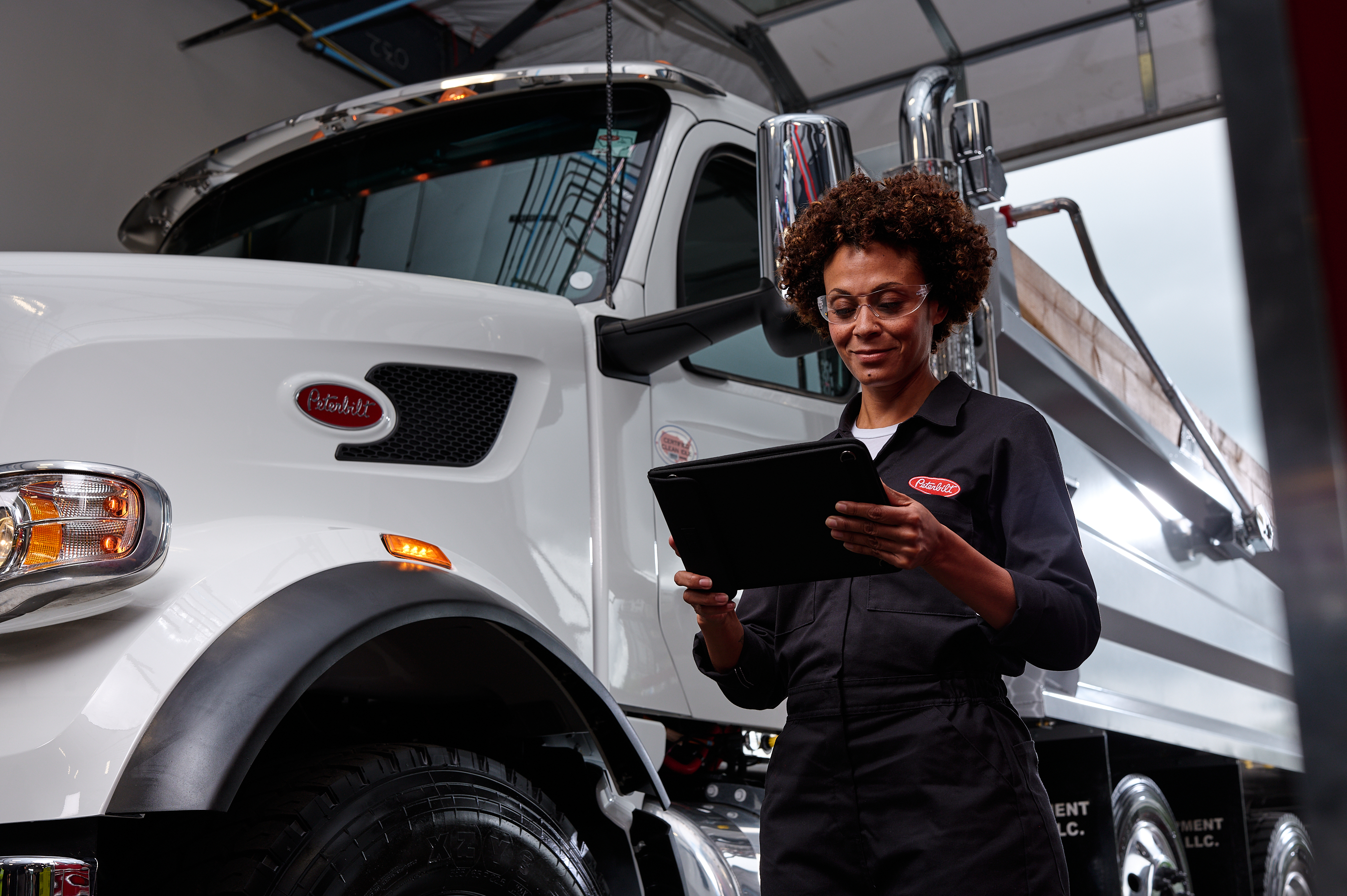 A Peterbilt technician adds coolant to a truck